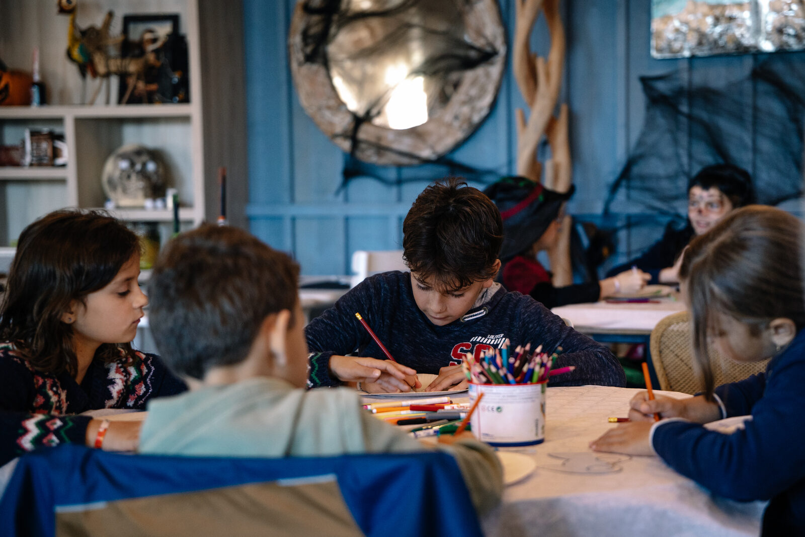 Children gathered around a long table for the Halloween craft workshop